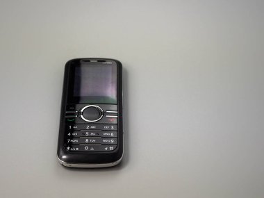 Old push button mobile phone. Broken phone. Phone on a gray background.