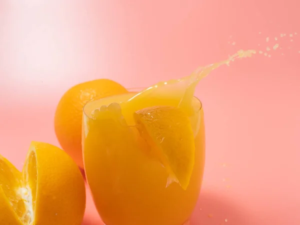 Orange and orange slice. Orange Juice Splashing. Orange on a pink background. Orange close up.