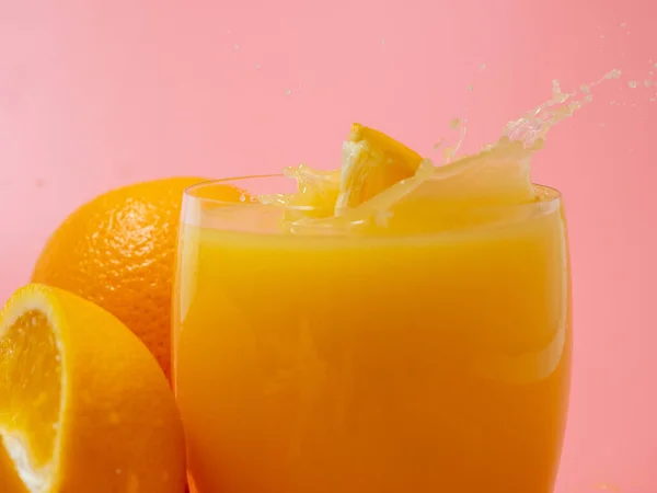 Orange and orange slice. Orange Juice Splashing. Orange on a pink background. Orange close up.