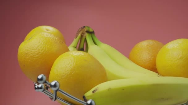 Бананы Апельсины Розовом Фоне Вращающиеся Фрукты Высококачественные Кадры — стоковое видео