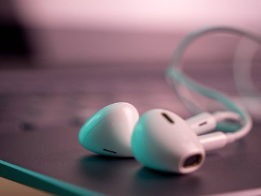 White headphones with a cable on a laptop. Close-up.