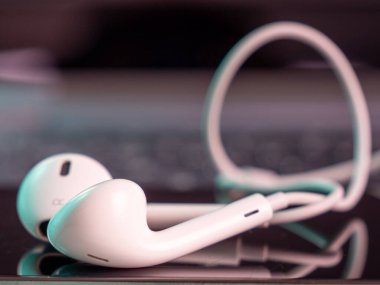 Smartphone has white headphones with a cable. Close-up.
