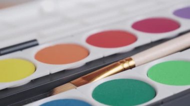 Brushes and watercolor paints on a white background. High quality 4k footage