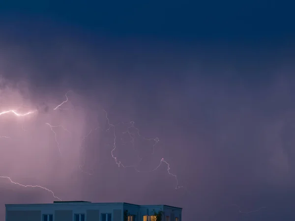 Lightning sparkles over the houses of the city during a thunderstorm. Thunderstorm with lightning. Dramatic mood.