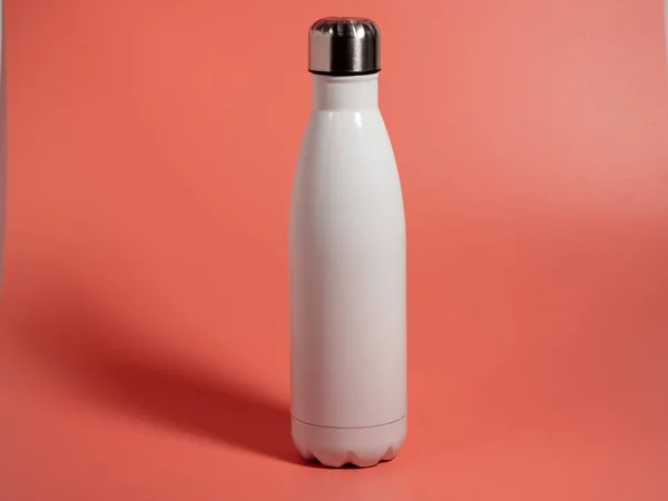 Pembe arka planda beyaz termal şişe. Termos şişesi. Yakın plan..