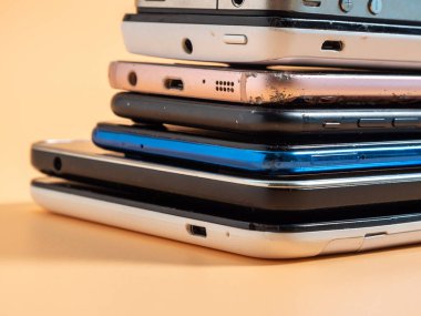 Eski bozuk akıllı telefonlar. Turuncu arka planda akıllı telefonlar. Yakın plan..
