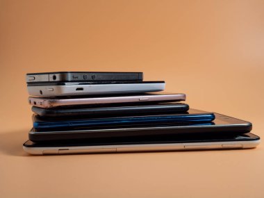 Eski bozuk akıllı telefonlar. Turuncu arka planda akıllı telefonlar. Yakın plan..