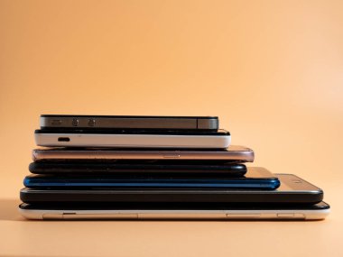Eski bozuk akıllı telefonlar. Turuncu arka planda akıllı telefonlar. Yakın plan..