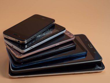 Eski bozuk akıllı telefonlar. Turuncu arka planda akıllı telefonlar. Yakın plan..