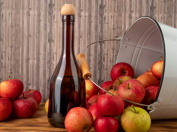 Apple cider vinegar in a bottle with apples on a wooden background. Apple cider vinegar and apples.