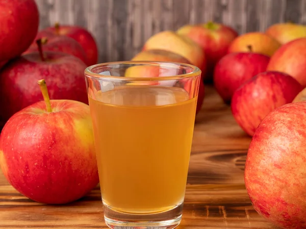 Apple cider vinegar in a glass with apples on a wooden background. Apple cider vinegar and apples.