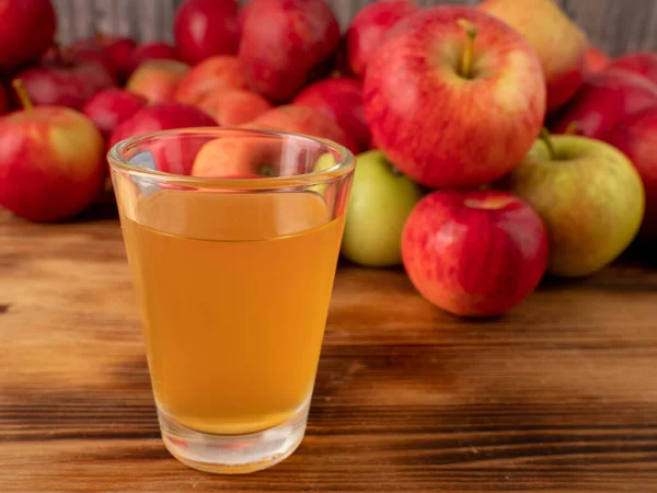Apple cider vinegar in a glass with apples on a wooden background. Apple cider vinegar and apples.
