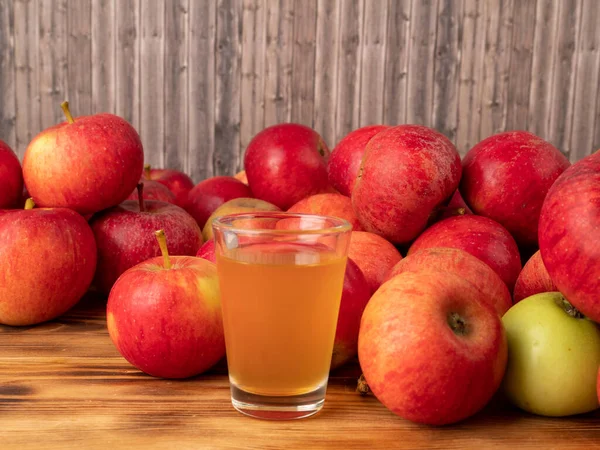 Apple cider vinegar in a glass with apples on a wooden background. Apple cider vinegar and apples.