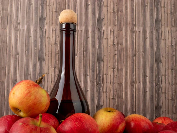 Apple cider vinegar in a bottle with apples on a wooden background. Apple cider vinegar and apples.