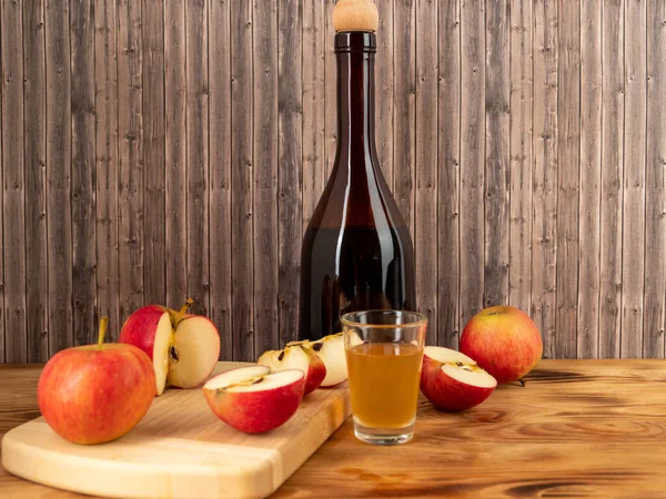 Apple cider vinegar in a bottle with apples on a wooden background. Apple cider vinegar and apples.