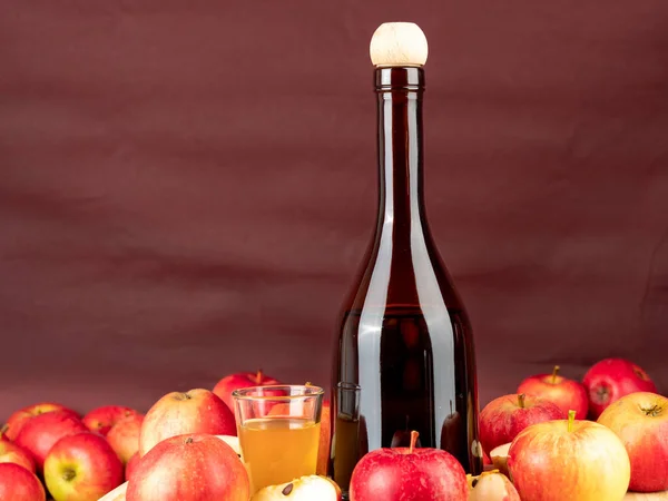 Apple cider vinegar in a bottle with apples on a brown background. Apple cider vinegar and apples.