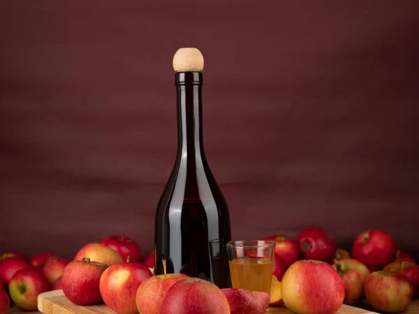 Apple cider vinegar in a bottle with apples on a brown background. Apple cider vinegar and apples.