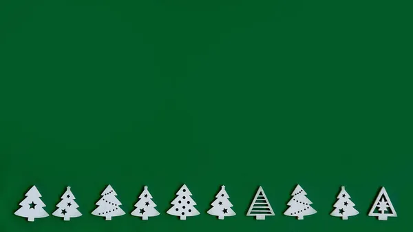 Albero di Natale creativo fatto di piccole figure di alberi di Natale su sfondo verde, un concetto di Natale con un posto per il testo — Foto Stock