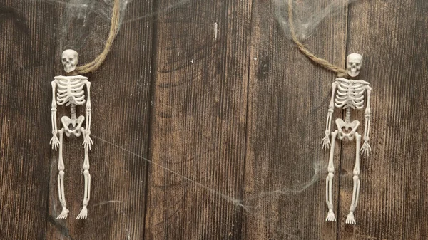 Esqueletos de brinquedo de um homem em uma corda em um fundo de madeira, conceito de Halloween — Fotografia de Stock