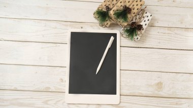 Yeni yıl hediyeleri, Noel konsepti, hediyeler, Kara Cuma ve siber pazartesi içeren beyaz ahşap arka planda bir tablet.