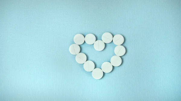 White heart-shaped pills on a blue background , the concept of Christmas and medicine — Stock Photo, Image