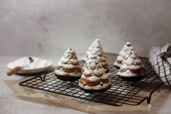 Cupcakes de Natal na forma de árvores de Natal em açúcar em pó em um fundo cinza, lei plana — Fotografia de Stock