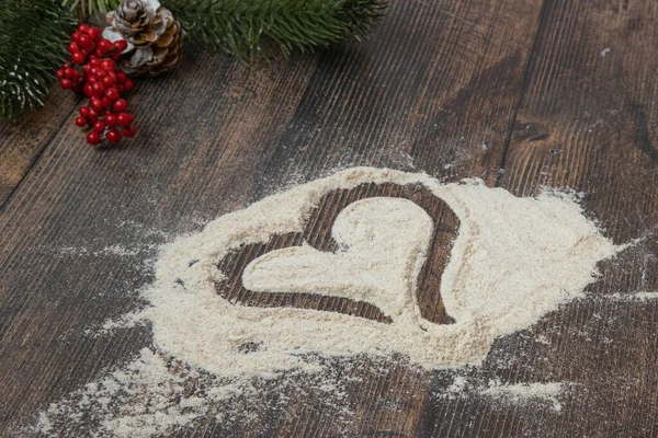 Christmas wooden background a heart painted on scattered flour — Stock Photo, Image