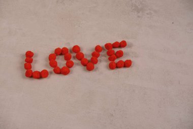 Aşk sözcüğü ve kırmızı arkaplandaki yumuşak toplardan yapılmış bir kalp Sevgililer Günü konsepti ve tüm aşıklar.