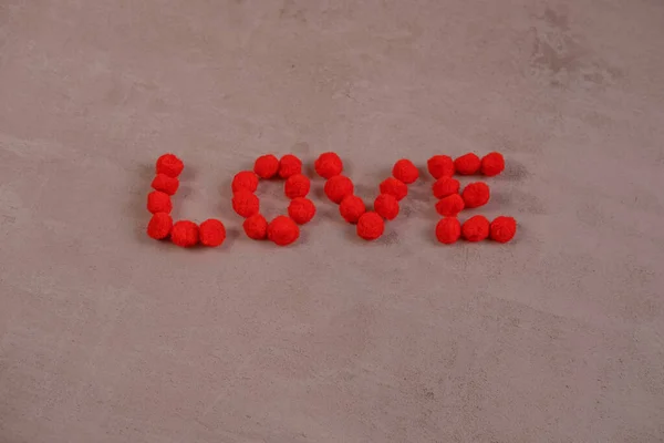 Le mot amour et un coeur fait de boules moelleuses sur un fond rouge.le concept de Saint Valentin et tous les amoureux — Photo