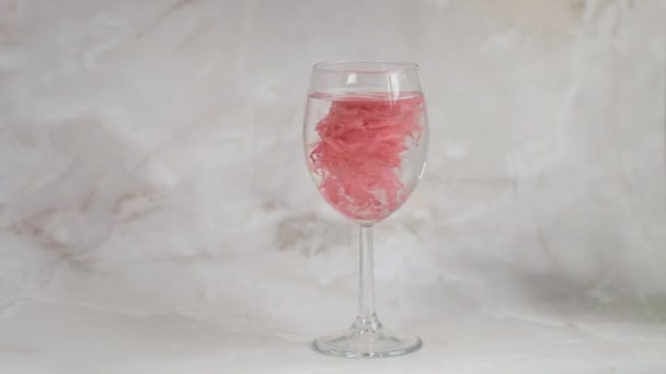 영구적 인 입술 화장을 위한 붉은 색소가 물컵에 서서히 녹아 간다 — 비디오