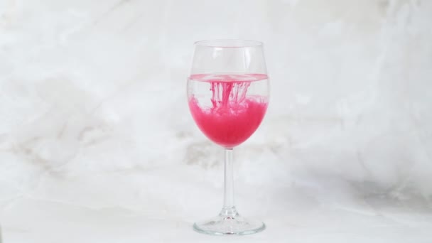 Pigmento rosso per il trucco permanente del labbro si dissolve lentamente in un bicchiere d'acqua — Video Stock