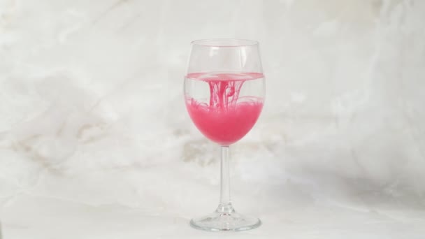 Pigmen merah untuk riasan bibir permanen perlahan larut dalam segelas air — Stok Video