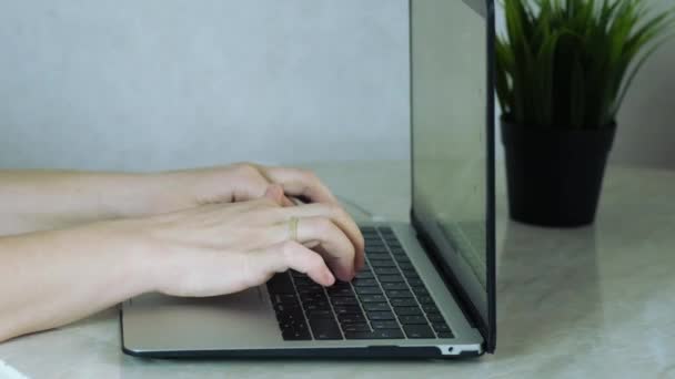 Händerna på en ljushyad person typ text på en bärbar dator — Stockvideo