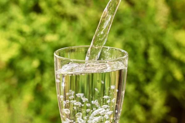 Despejando Água Potável Vidro Sobre Fundo Natureza Verde Turva — Fotografia de Stock