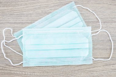 Ahşap arka planda iki tıbbi yüz maskesi.