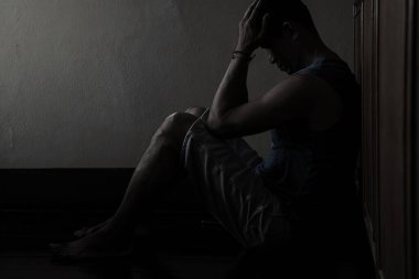 Elleri havada umutsuz bir adam karanlık bir köşede oturuyor. 