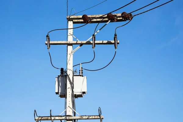 Power supply transformer on electricity pole on blue sky background