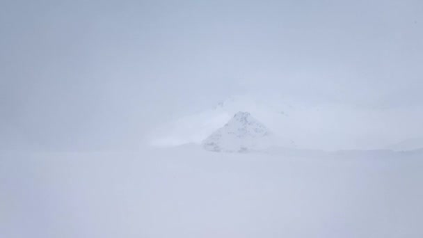 Ağır çekim. Şiddetli bir rüzgarla kar fırtınasının zirvesine bakan dağ manzarası.. — Stok video