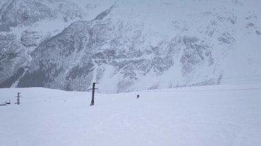 Ağır çekim. İHA saldırısı. Yalnız bir snowboardcunun karlı havada dağ yamacından aşağı inişi...