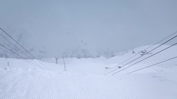 Ağır çekim. Kar kaplı dağ yamaçlarının ve kayak merkezindeki teleferiğin üst görüntüsü... — Stok video