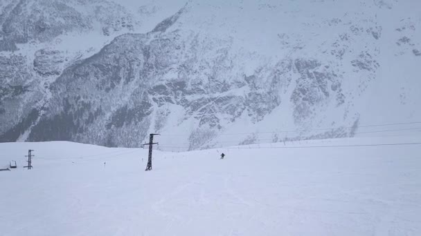 Zwolnij trochę. Strzelanie dronami. Widok z góry samotnego snowboardzisty schodzącego z góry w śnieżnej pogodzie.. — Wideo stockowe
