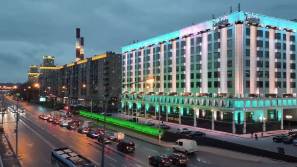 24.11.2021 Moscú. Vista aérea de la carretera con vehículos en movimiento, el hotel Radisson por la noche bajo la luz de farolas en Moscú cerca de la estación de tren Kievsky. — Vídeos de Stock