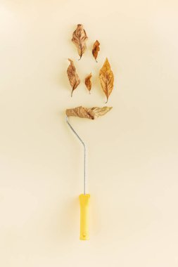 Parlak arka planda sonbahar yaprakları olan yaratıcı boya silindiri fikri. Minimum düz konsept. Resim ya da sonbahar ilhamı.