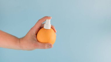 Mavi arka planda turuncu ve spreyden yapılmış yaratıcı bir düzenleme. Minimum meyve spreyi konsepti. Citrus kokusu ilham verir..