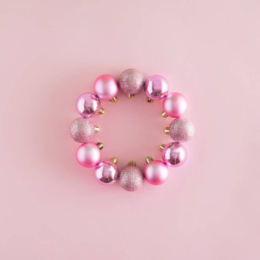 Pastel pembe arka planda daire şeklinde süs eşyalarından yapılmış yaratıcı bir Noel düzenlemesi. Asgari yeni yıl konsepti. Kopyalama alanı ilhamı ile çerçeve.