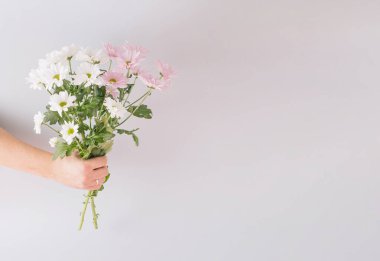 Gri arka planda bir buket çiçeğin oluşturduğu yaratıcı bahar düzenlemesi. Kopyalama alanı olan en küçük konsept.