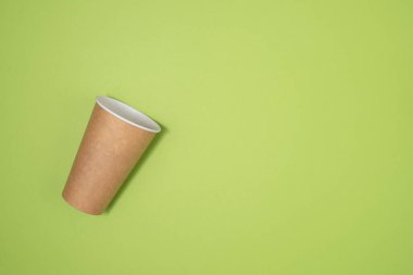 Kahve ya da çay için boş bir kağıt bardak yeşil arka planda yatar. 