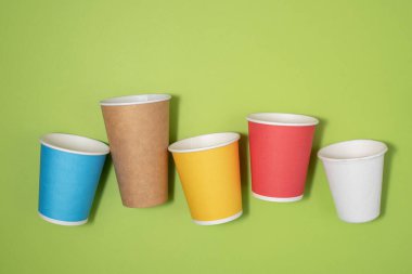 Yeşil arka planda çok renkli güzel eko kağıt parti fincanları