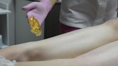 Bir kadının bacaklarındaki kılları ağda yaparak çıkarmak için yakın çekim prosedürü.