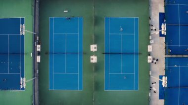 Tenis kortunun hava manzarası. Yavaş, yukarıdan aşağıya mavi açıkhava sahalarında antrenmandaki oyuncularla birlikte..